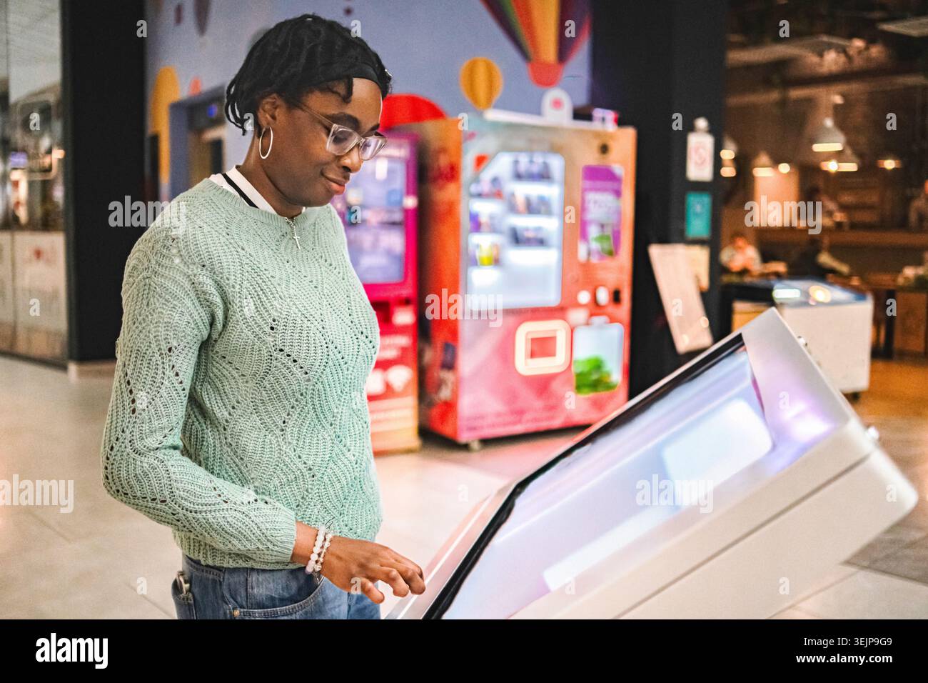 Woman using interactive digital kiosk for information display Stock Photo