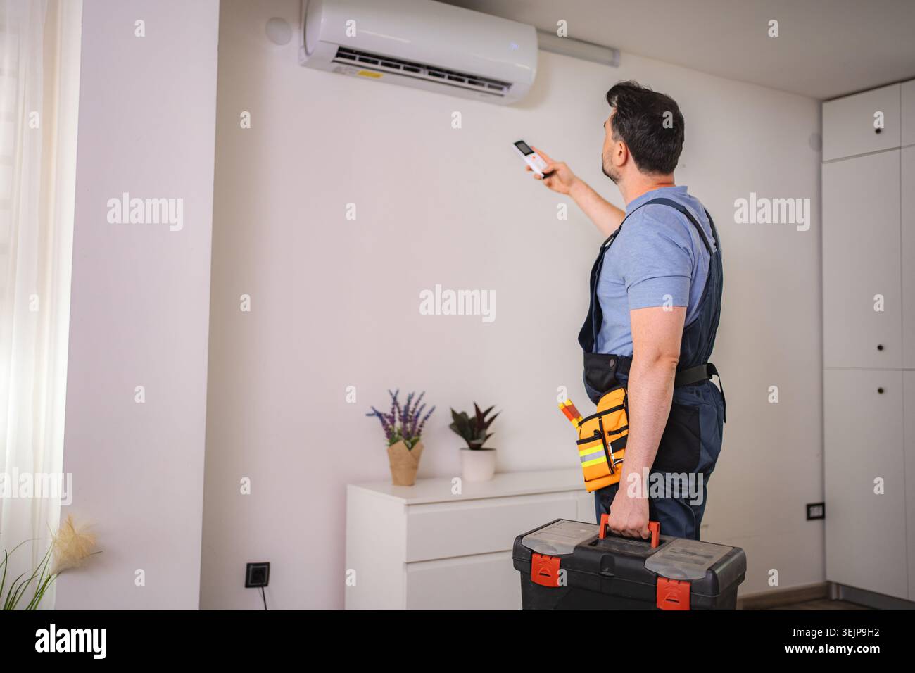 Technician testing air conditioning with remote control Stock Photo