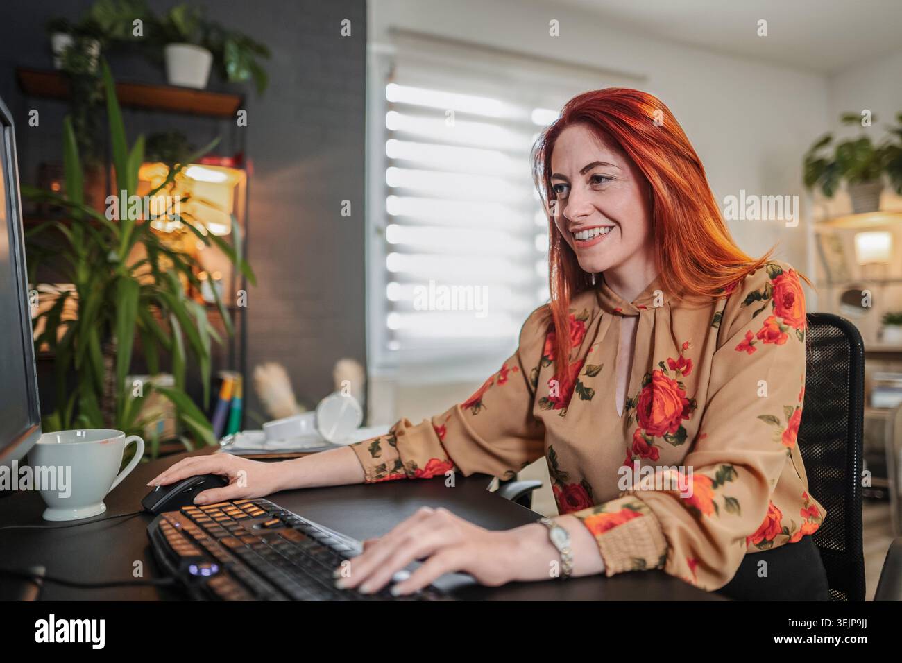 Smiling businesswoman working from home using desktop computer Stock Photo