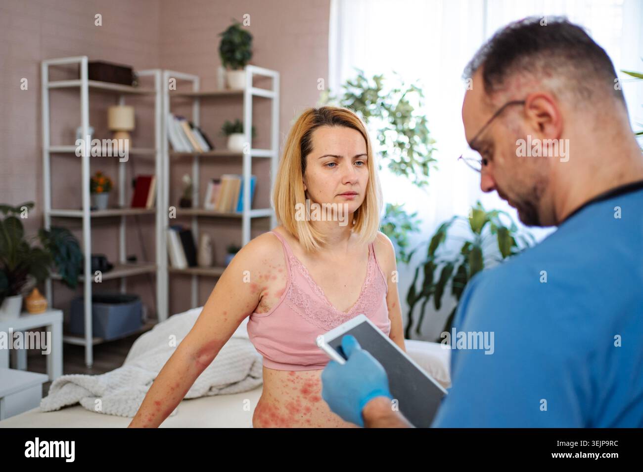 Doctor examining woman with skin rash using digital tablet Stock Photo