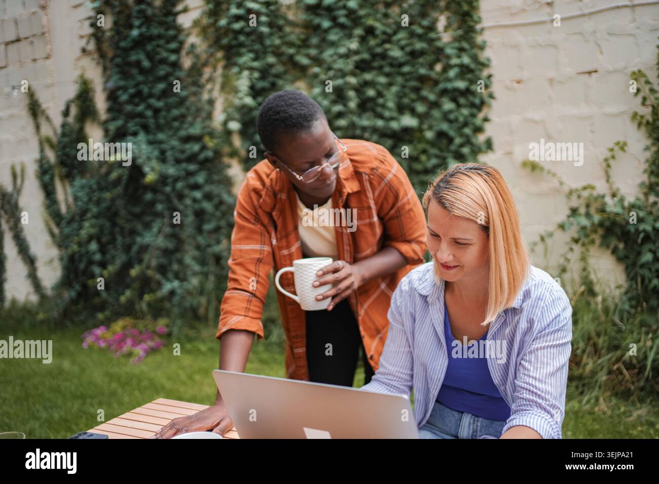 Two businesswomen collaborating on a project in a garden Stock Photo