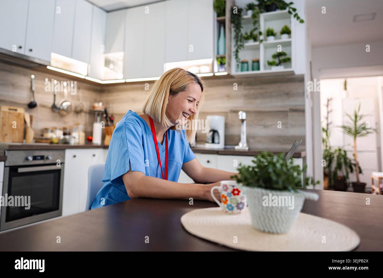 Female doctor working from home, using laptop and smiling Stock Photo