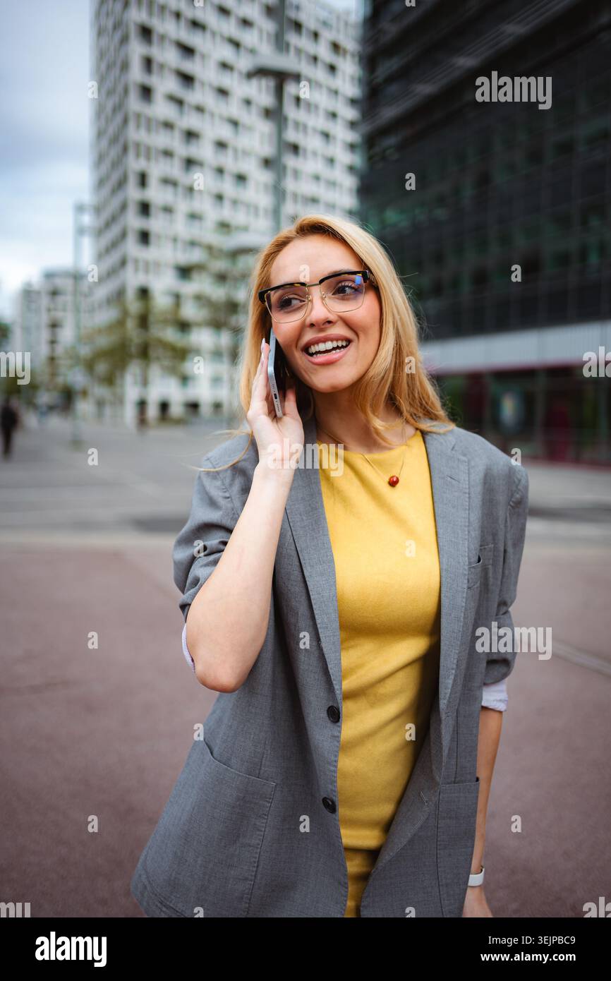 Young businesswoman talking on smartphone in urban setting Stock Photo