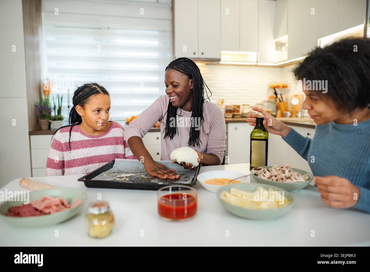 Family making pizza together in modern kitchen at home Stock Photo