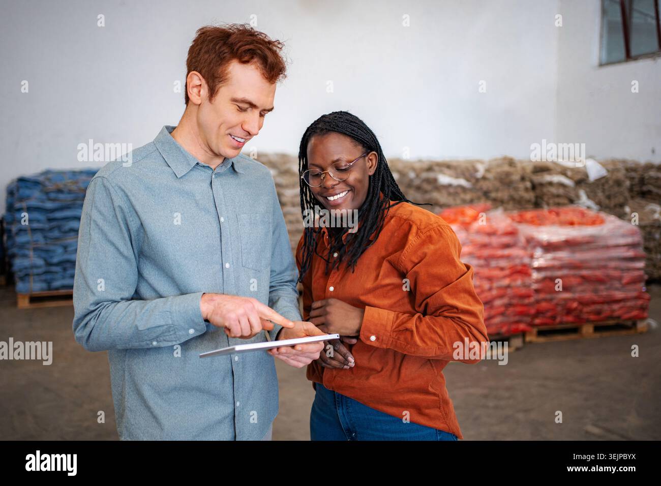 Warehouse workers collaborating on inventory management using digital tablet Stock Photo