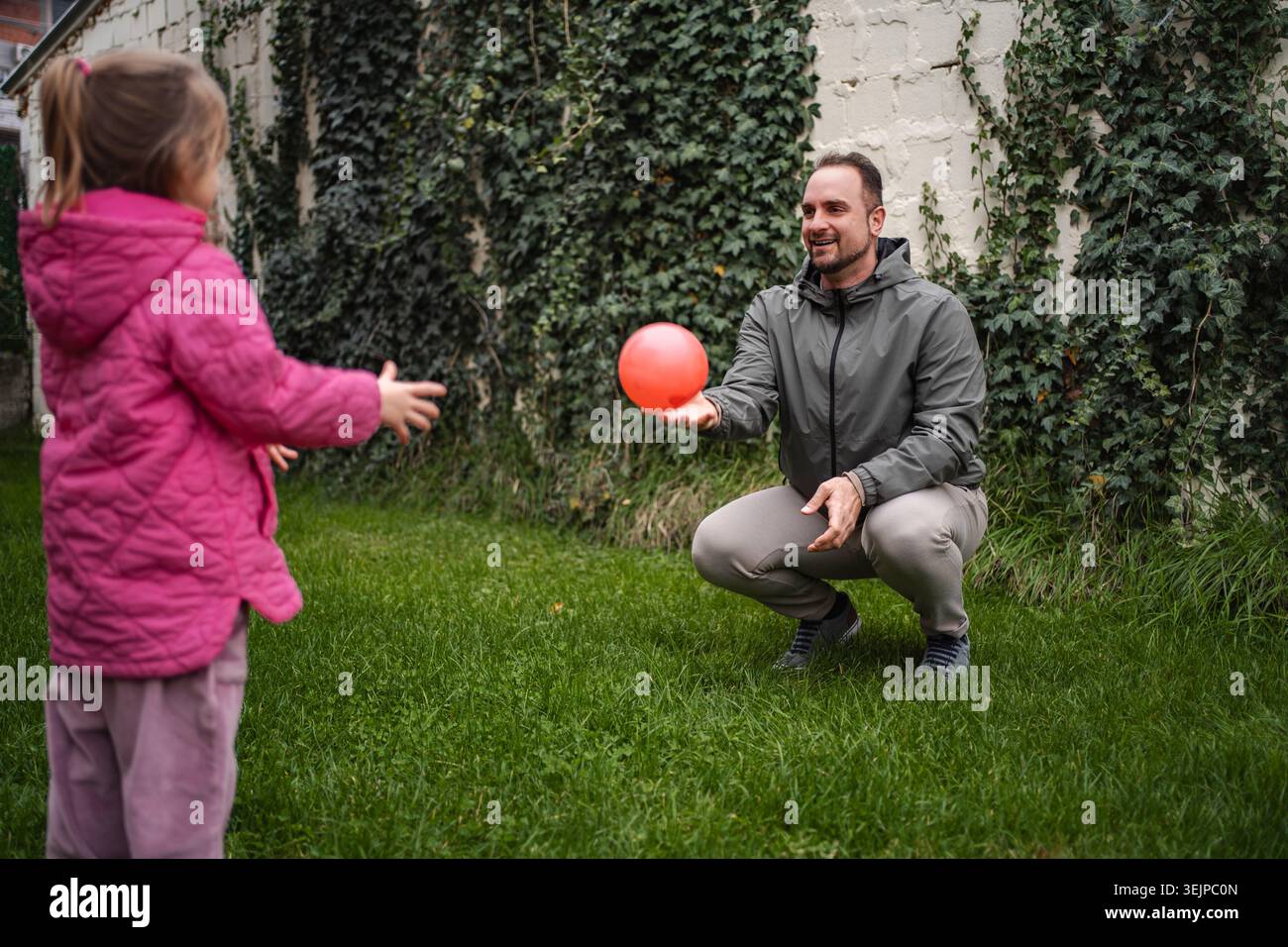 Father playing catch with daughter in backyard Stock Photo