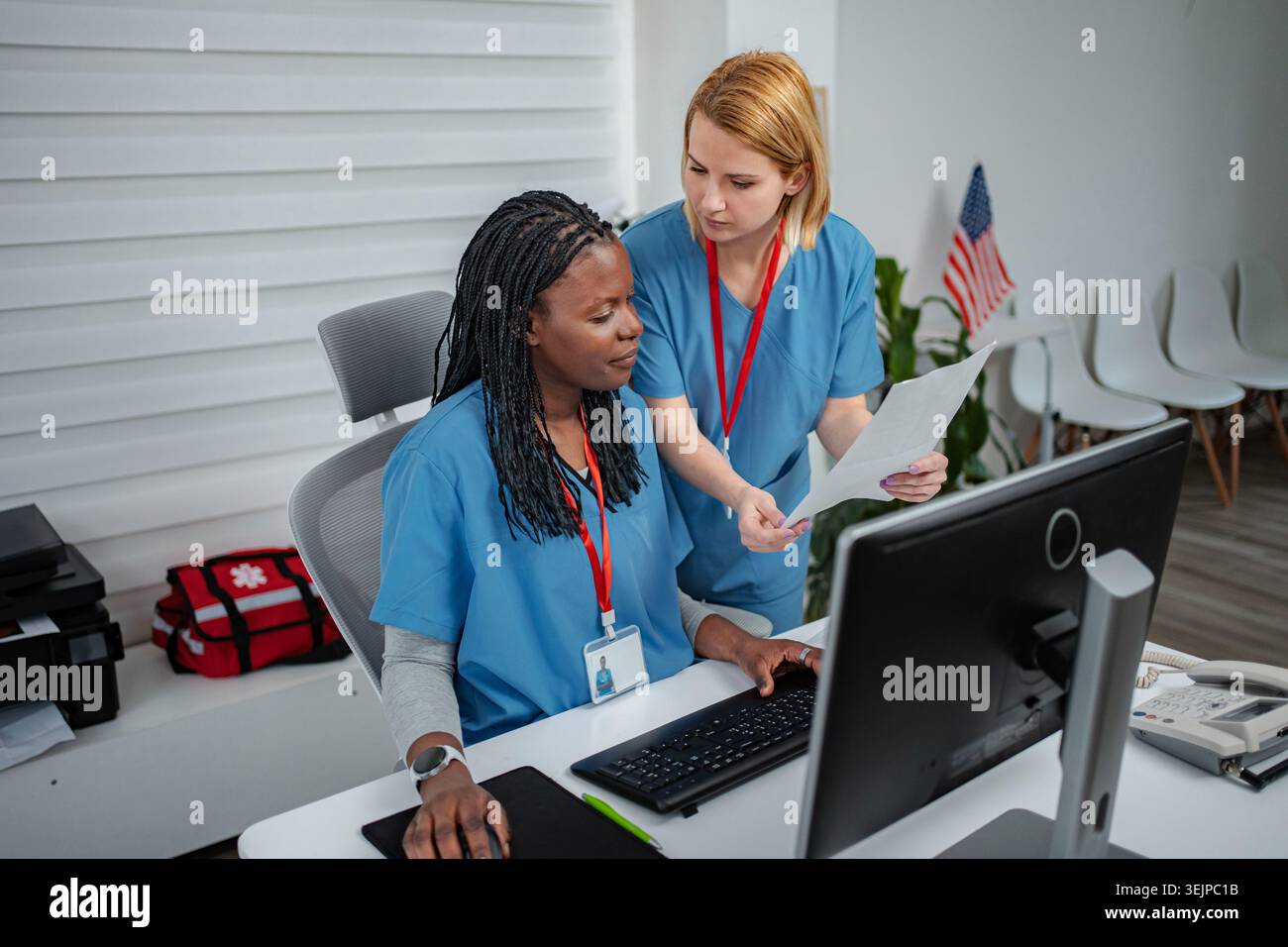 Two nurses collaborating on computer and paperwork at medical office Stock Photo