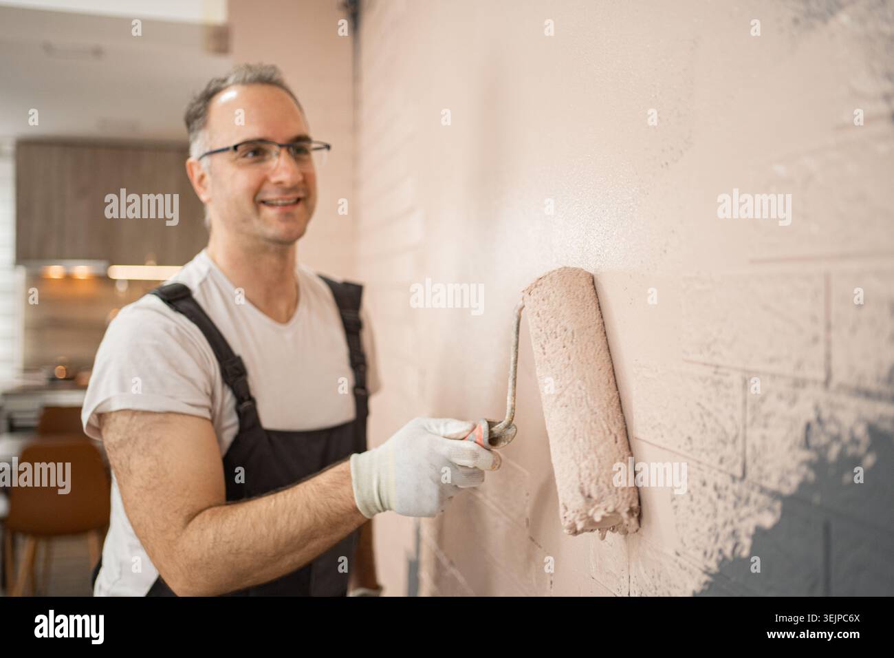 Man Painting Wall With Paint Roller Stock Photo