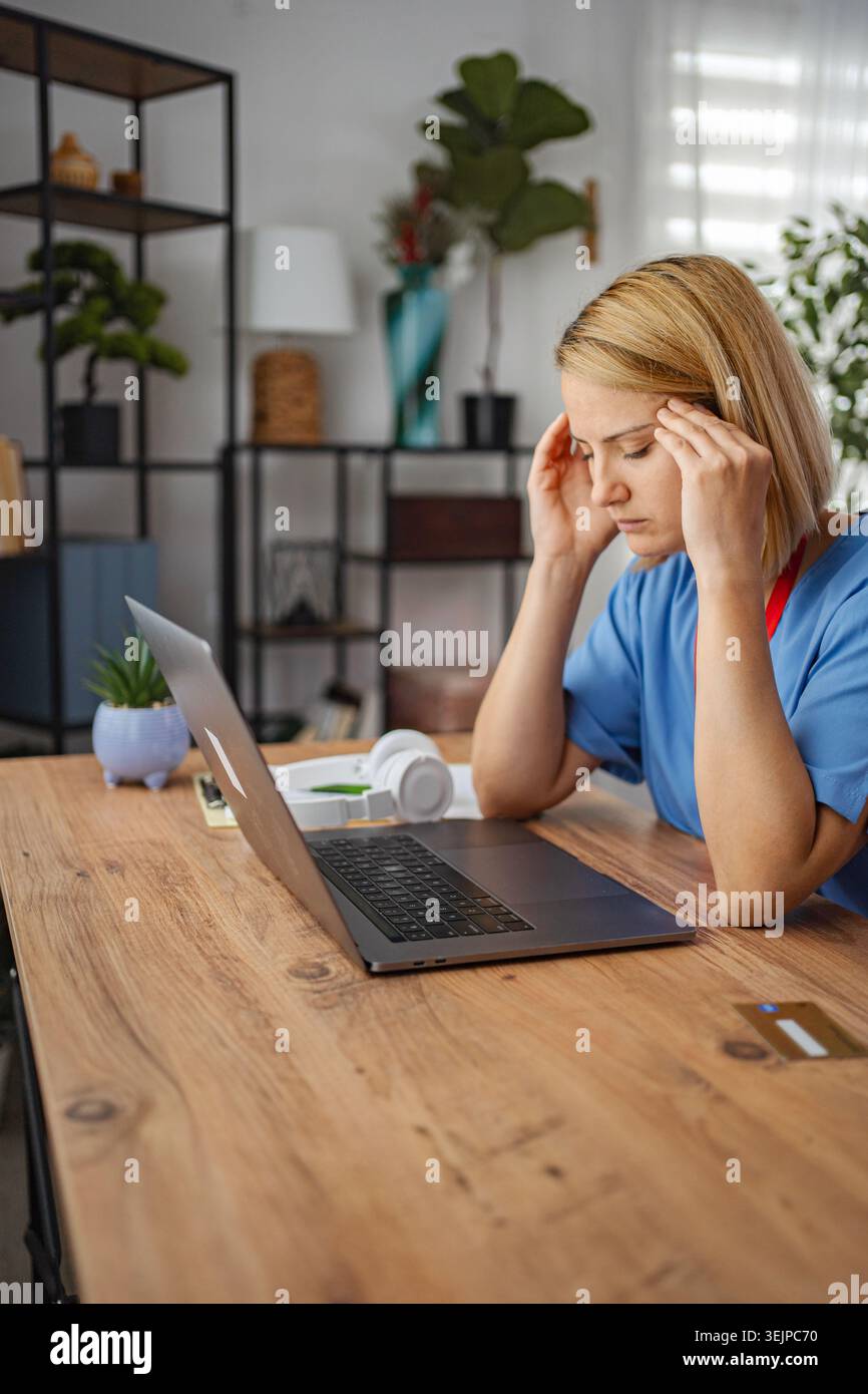 Stressed doctor having headache while working from home Stock Photo