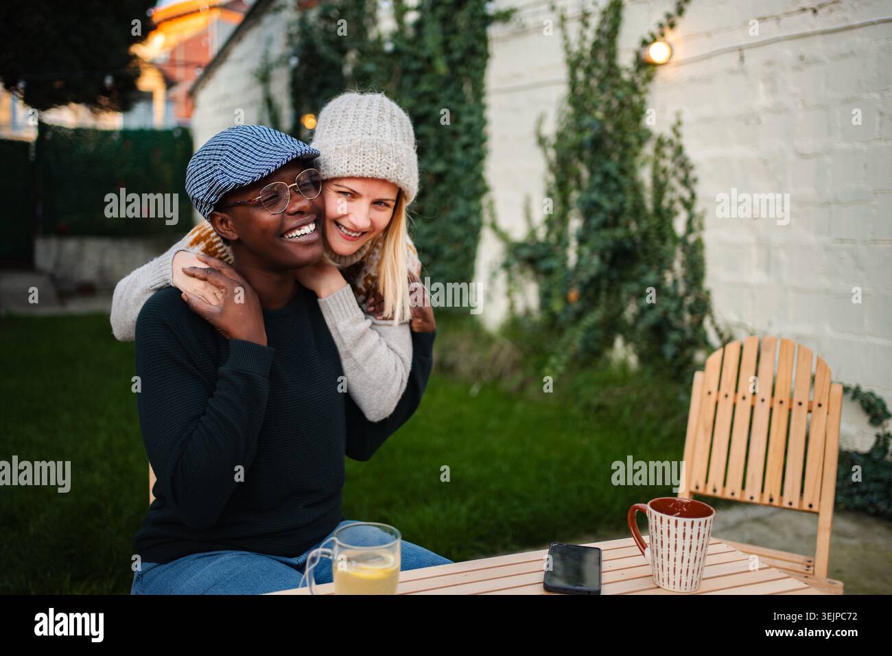 Happy diverse couple embracing at backyard table Stock Photo
