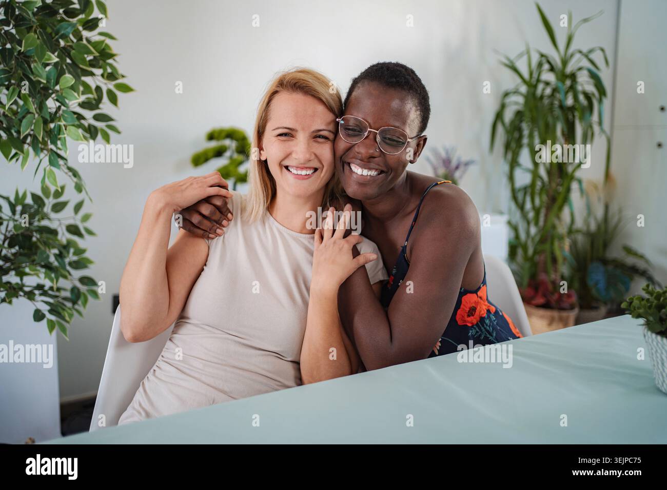 Two smiling friends hugging each other at home Stock Photo