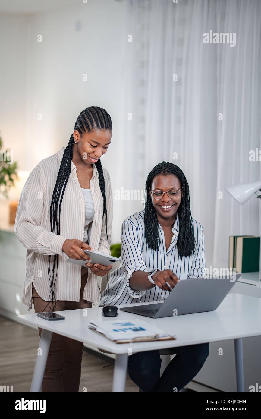 Two black women collaborating business ideas using technology Stock Photo