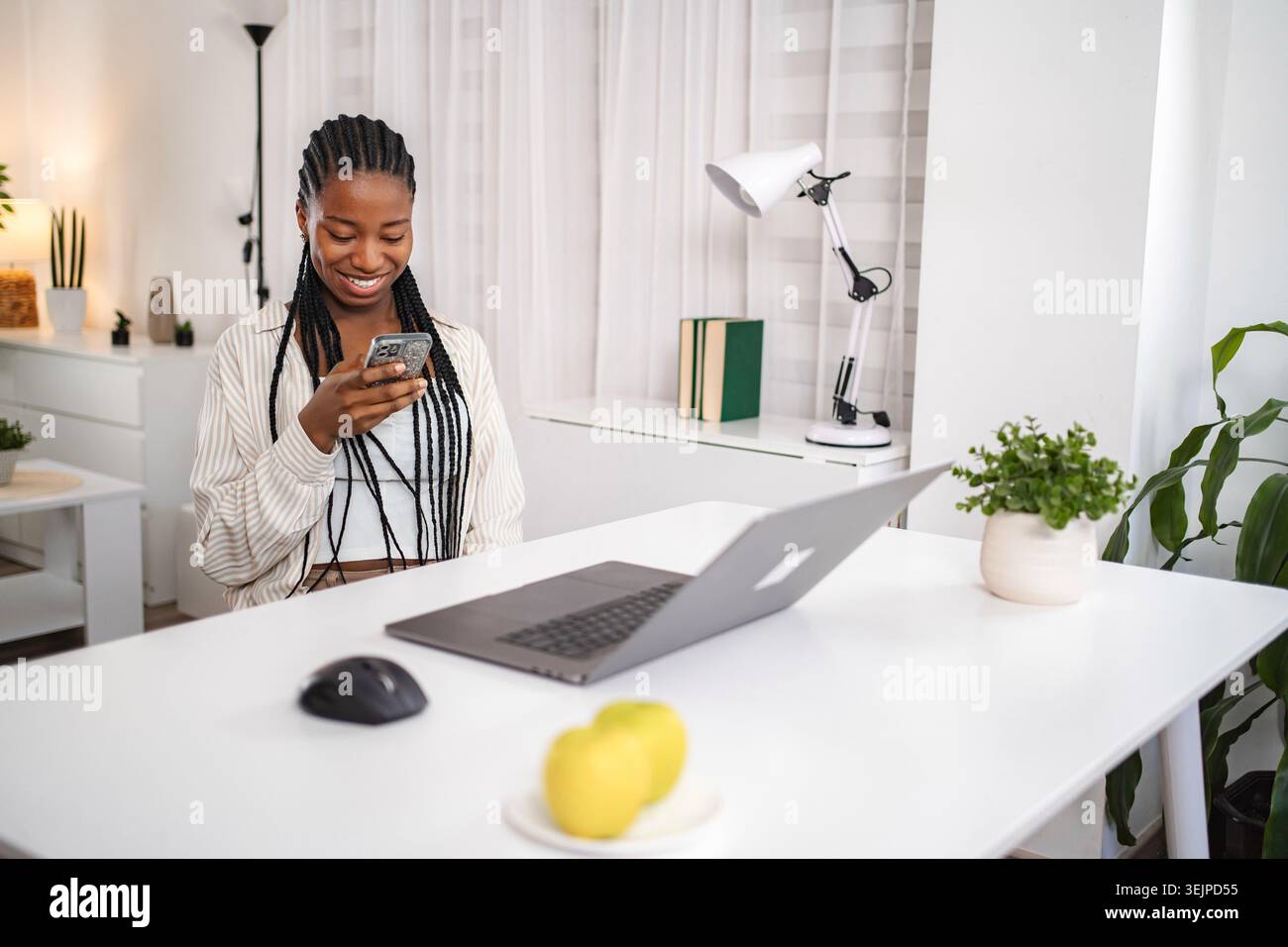 Young woman smiling using smartphone in home office Stock Photo