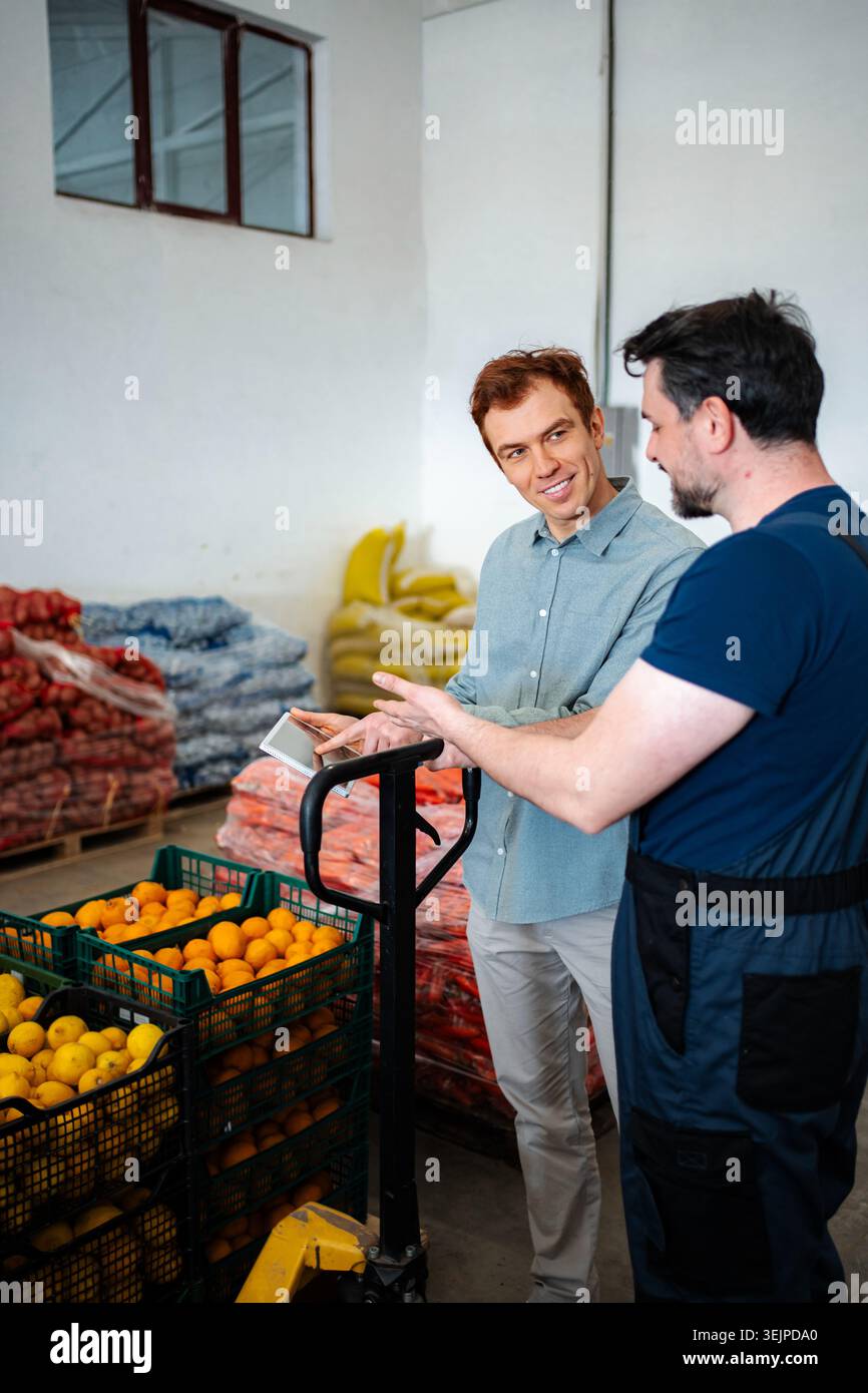 Warehouse workers discussing logistics and inventory on tablet Stock Photo