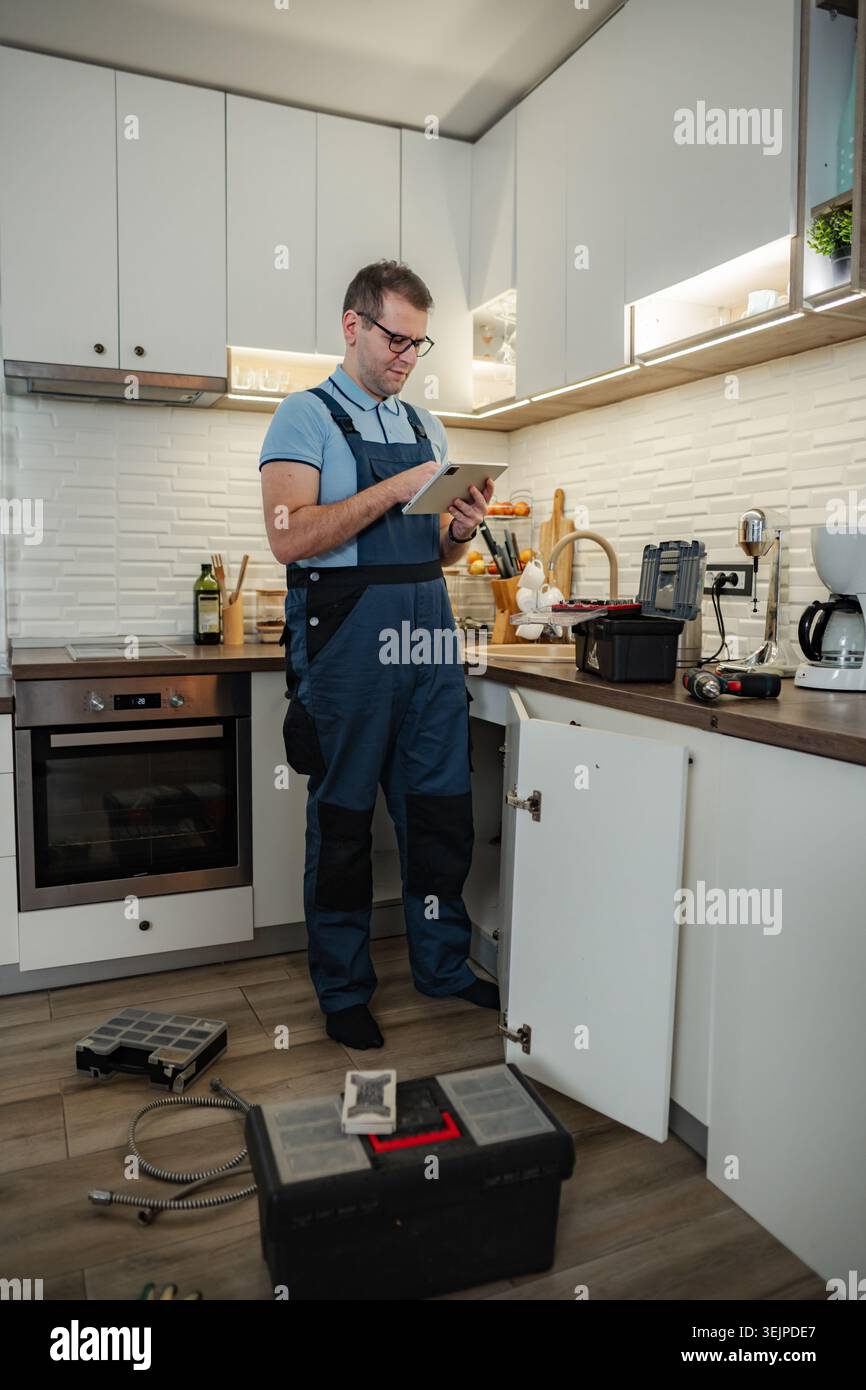 Plumber using digital tablet checking kitchen sink repair Stock Photo