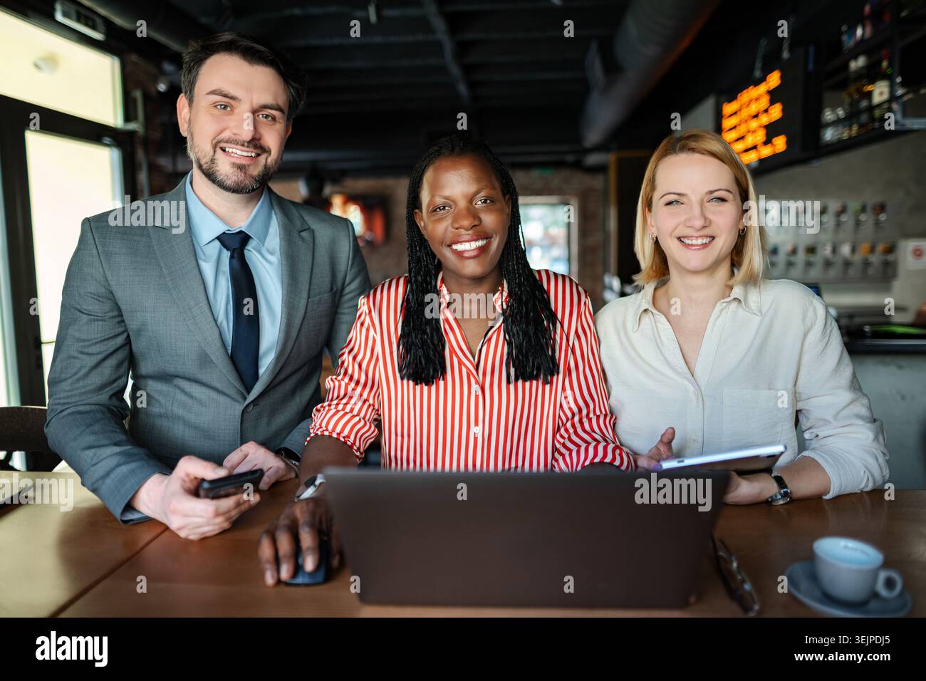 Diverse business team collaborating with technology in cafe Stock Photo