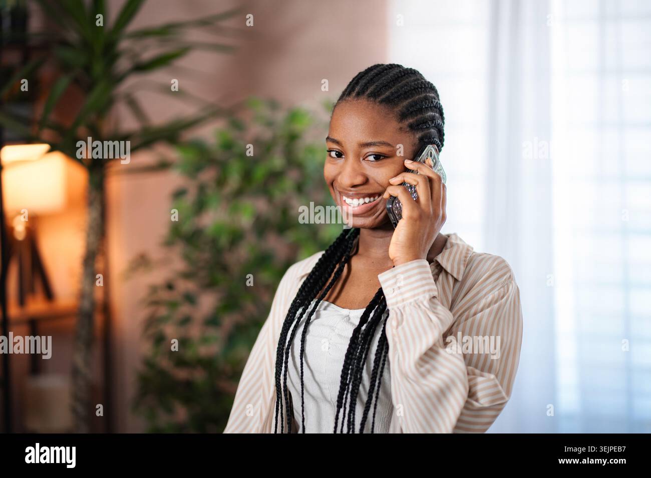 Young Black woman smiling talking on cellphone Stock Photo