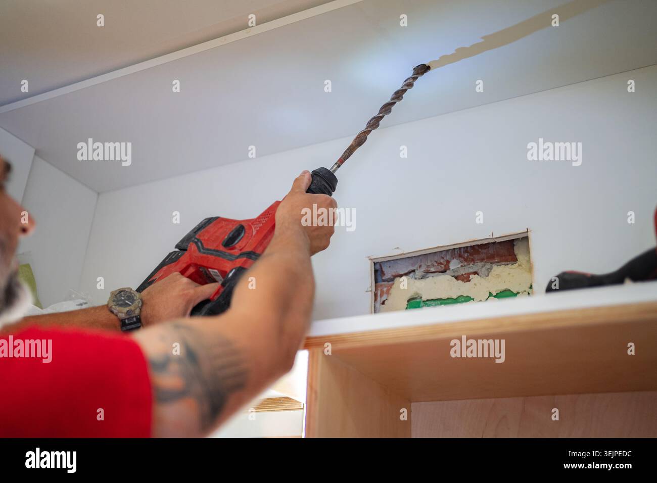 Contractor drilling a hole in the ceiling using a hammer drill Stock Photo