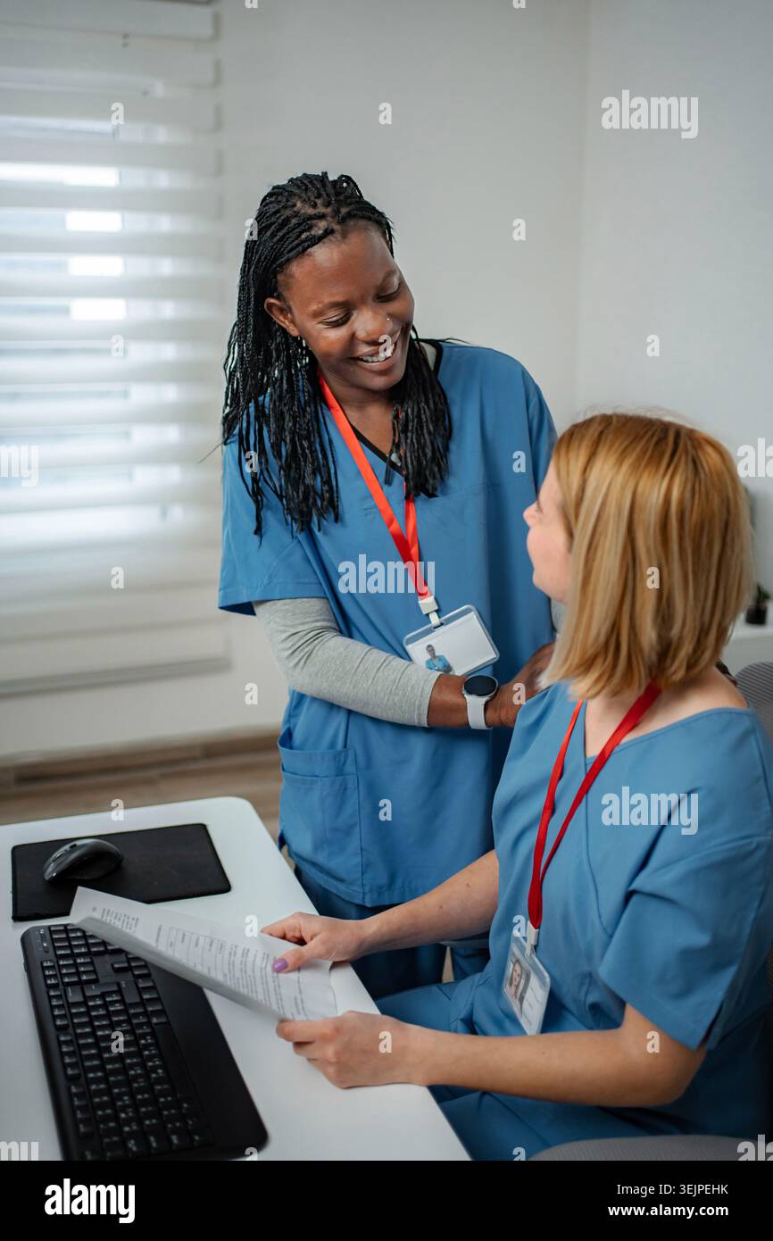 Diverse nurses collaborating on paperwork in modern office Stock Photo