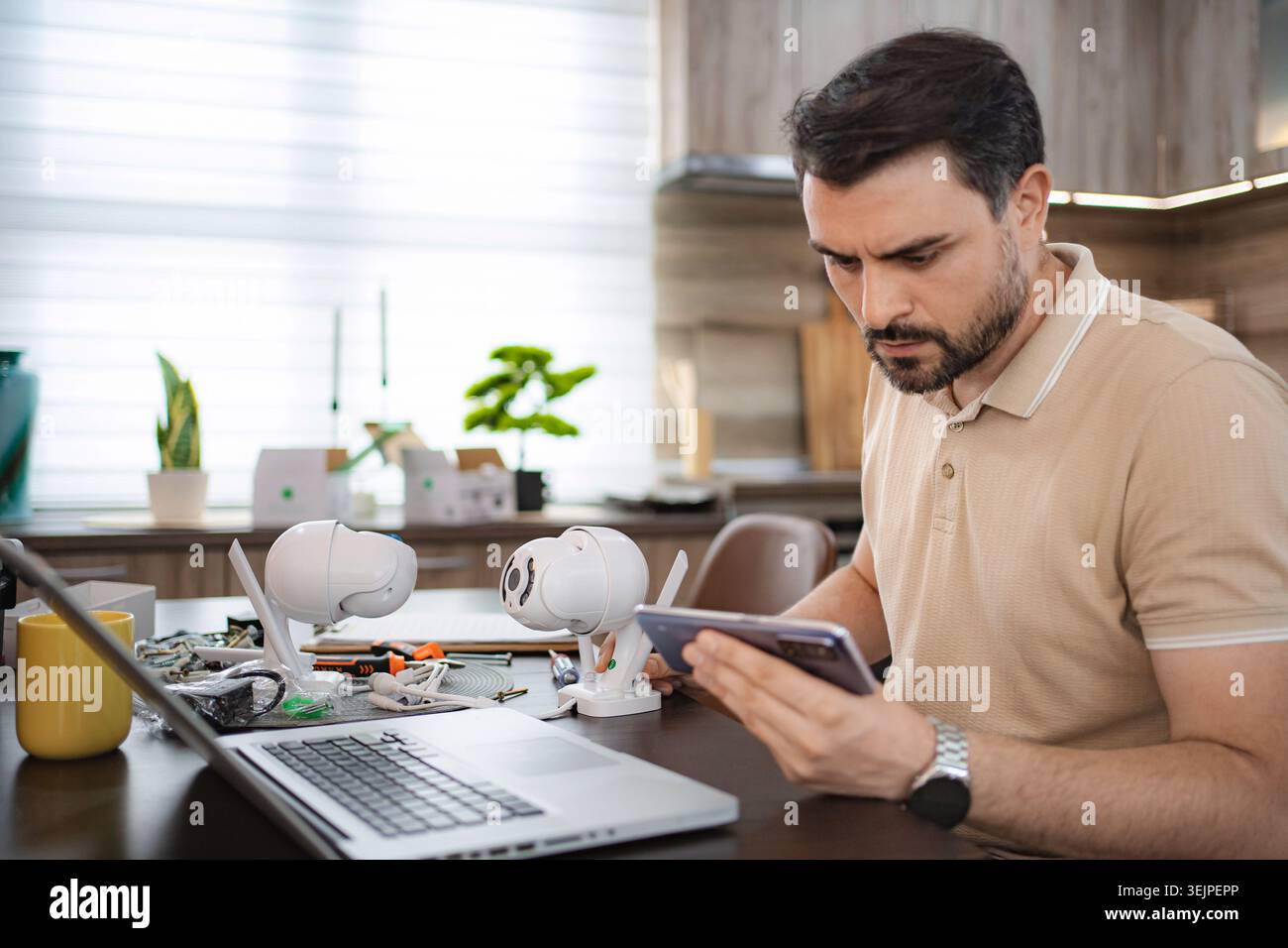 Technician configuring ip cameras using smartphone and laptop Stock Photo
