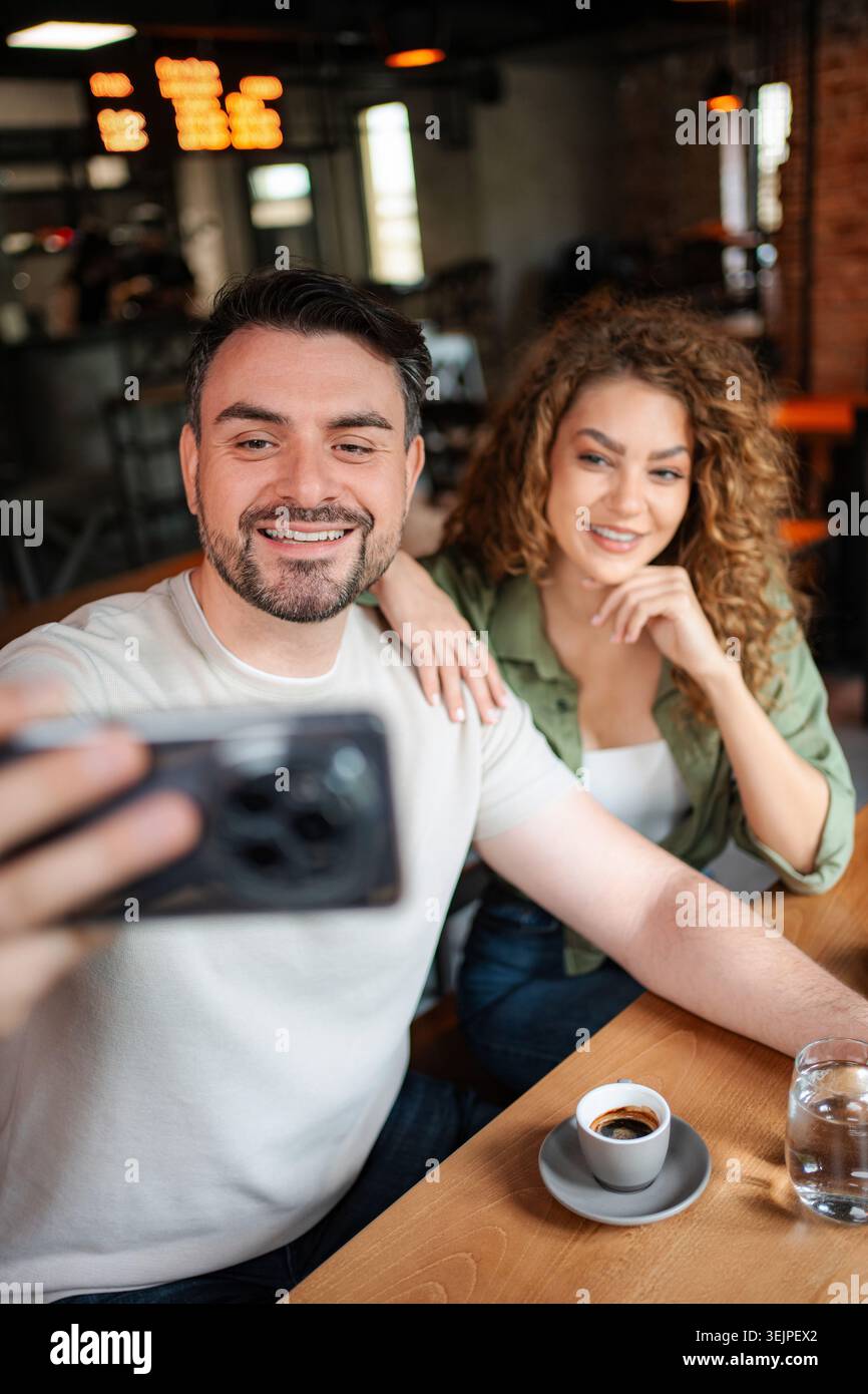 Couple taking a selfie while having coffee in a cafe Stock Photo