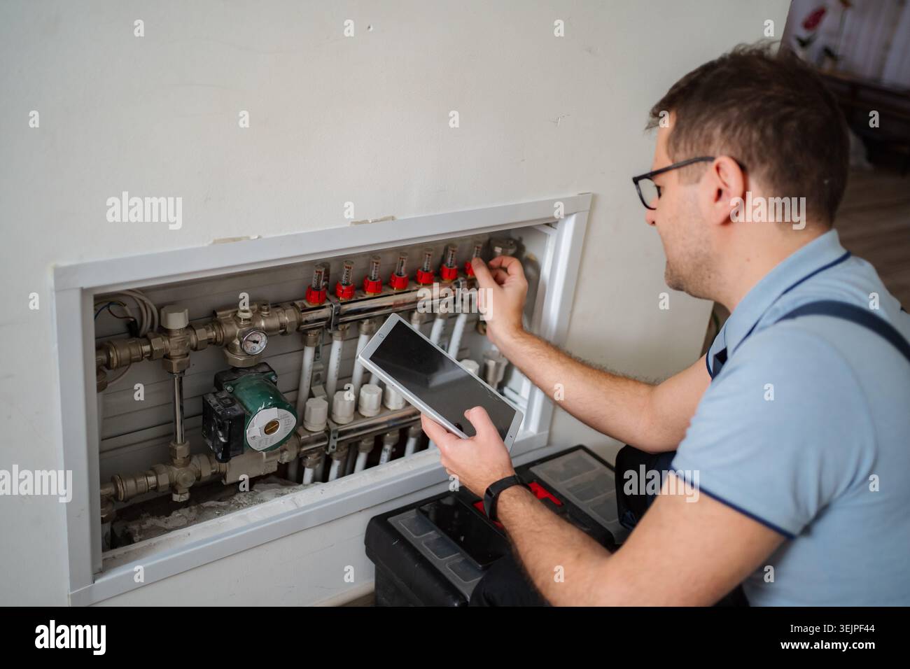 Technician working on underfloor heating system using digital tablet Stock Photo