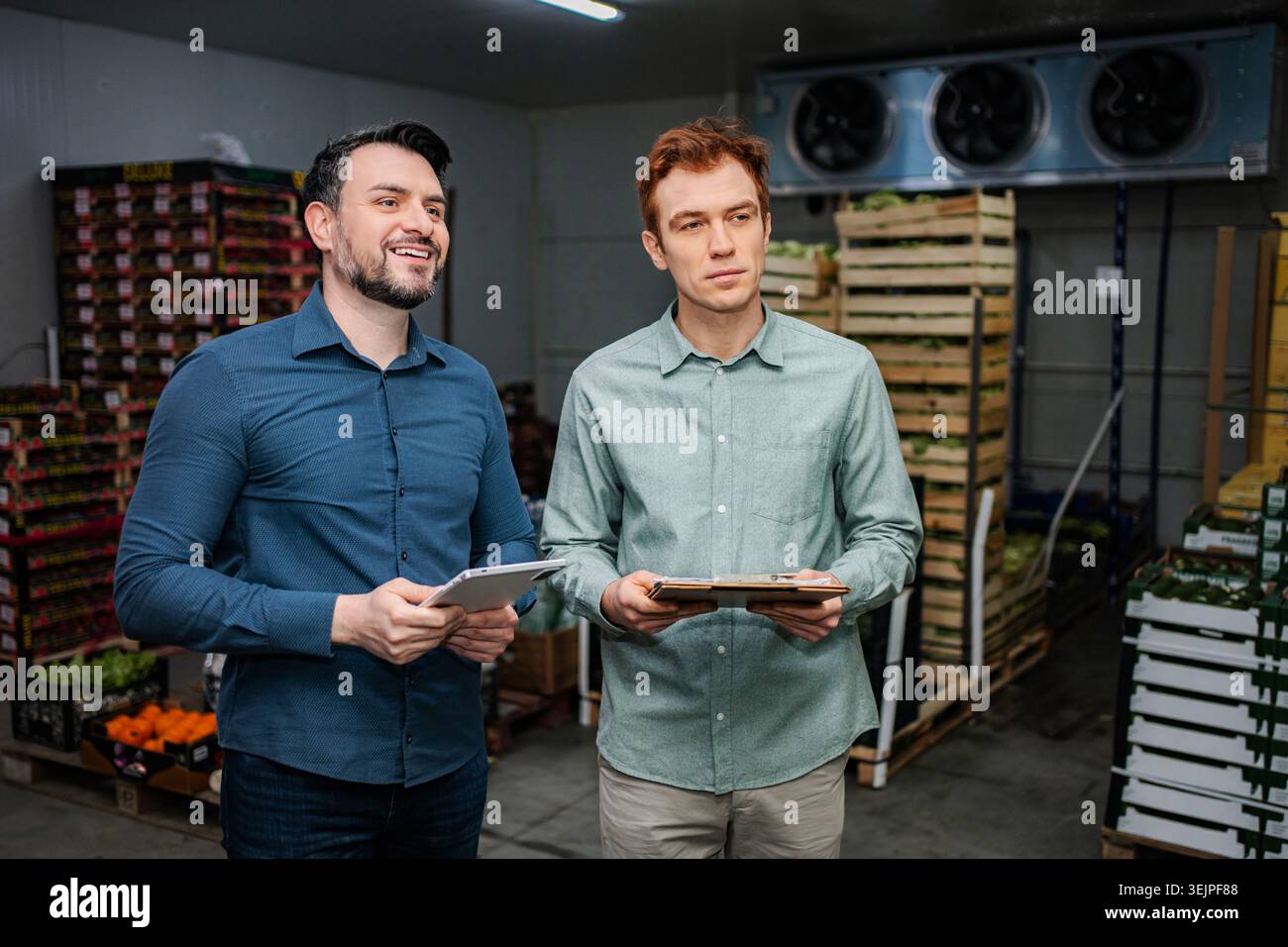 Produce managers inspecting inventory in cold storage warehouse Stock Photo