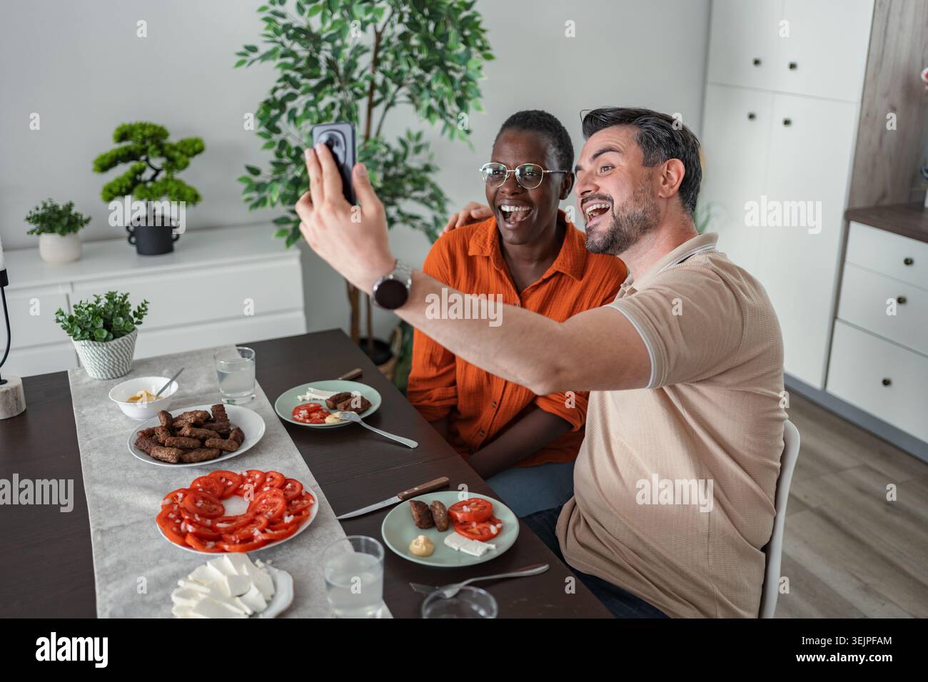 Happy couple taking selfie while having lunch at home Stock Photo