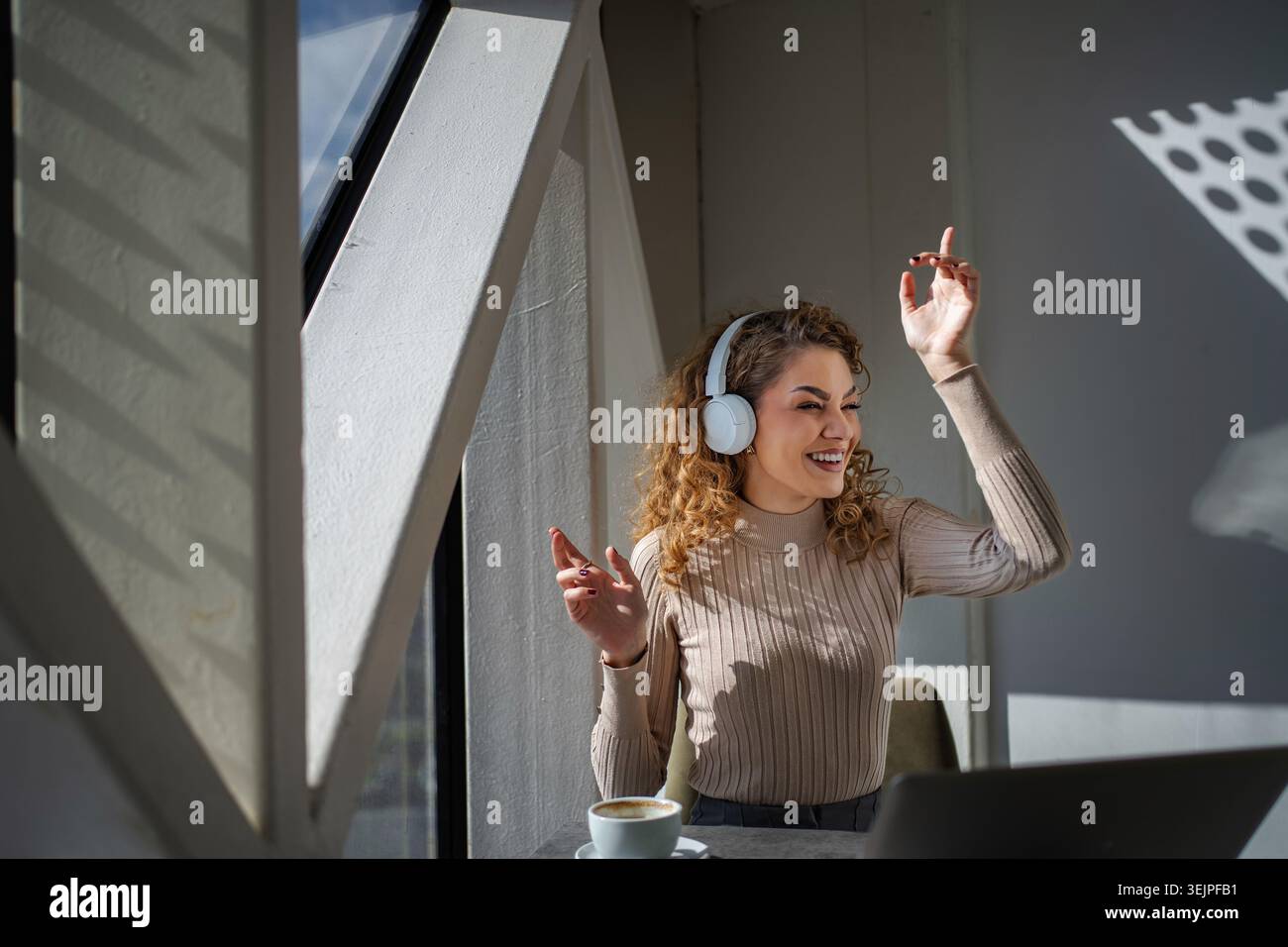 Young woman enjoying music with headphones remote working at cafe Stock Photo
