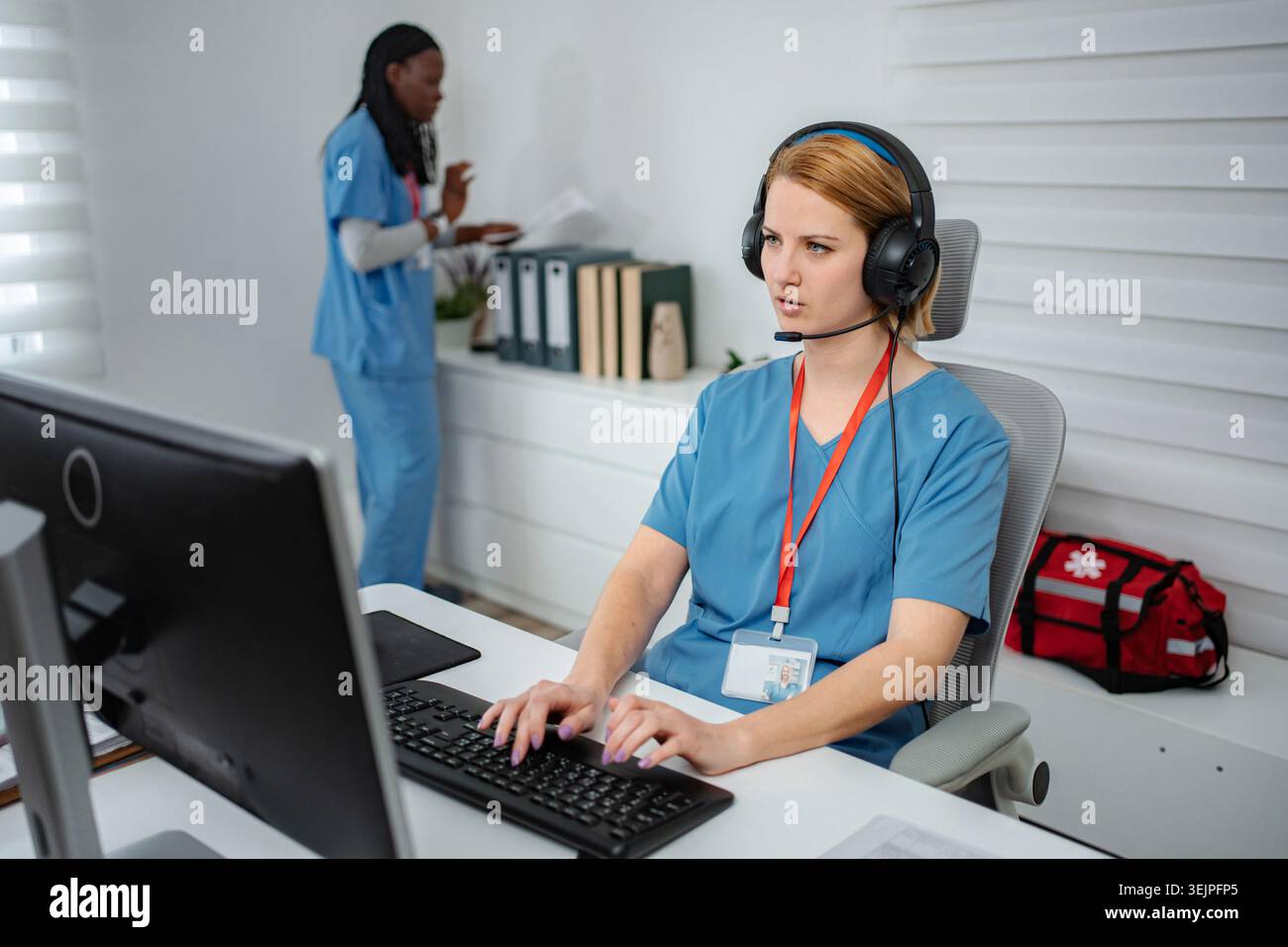 Healthcare employee talking on headset at computer Stock Photo