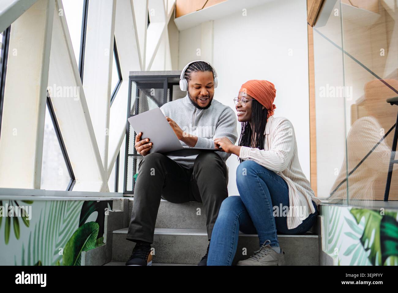 Diverse colleagues collaborating on laptop in modern coworking space Stock Photo