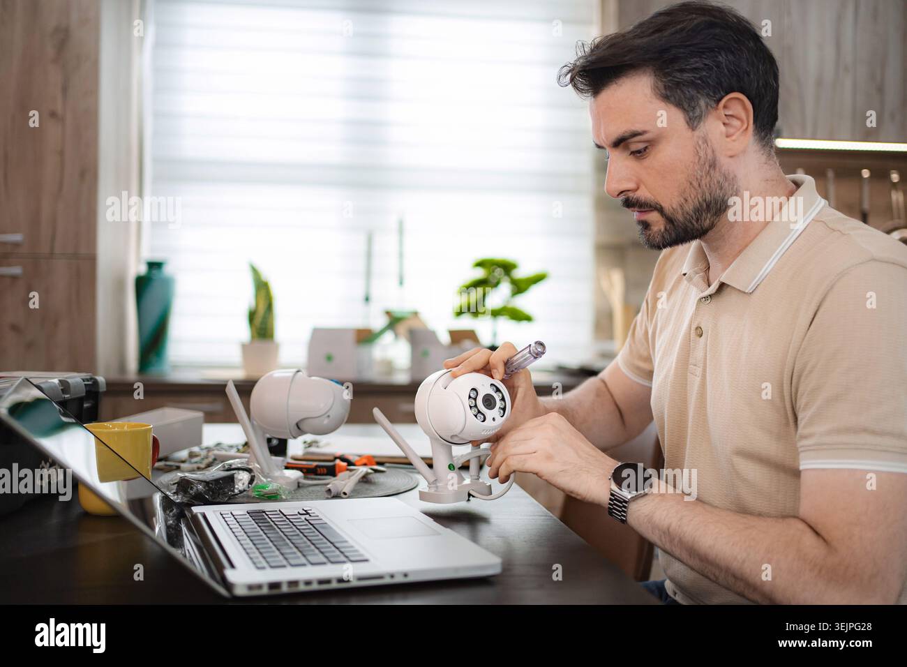Technician installing a surveillance camera at home using a laptop Stock Photo