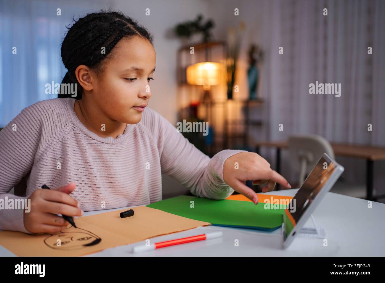 Girl drawing face while using digital tablet for remote learning Stock Photo