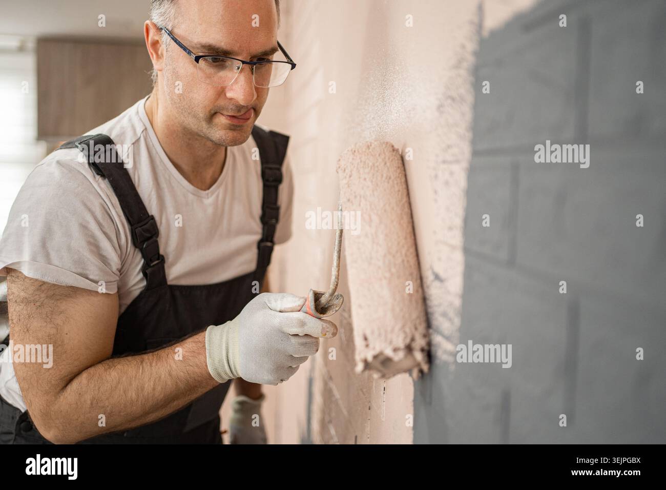 Man Painting Wall With Paint Roller Stock Photo