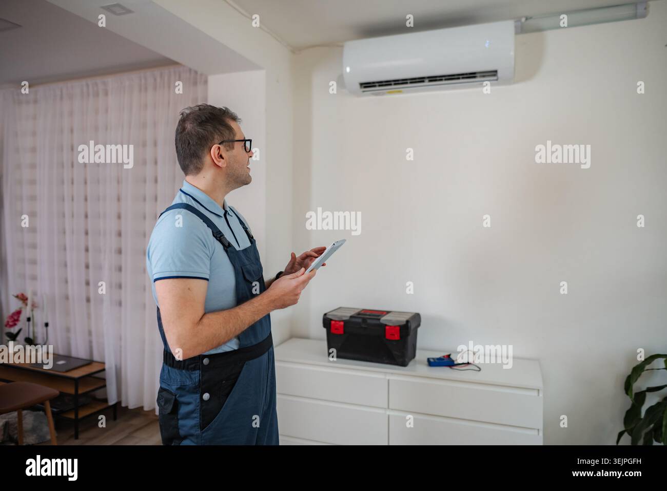 Technician checking air conditioning unit using a digital tablet for maintenance Stock Photo