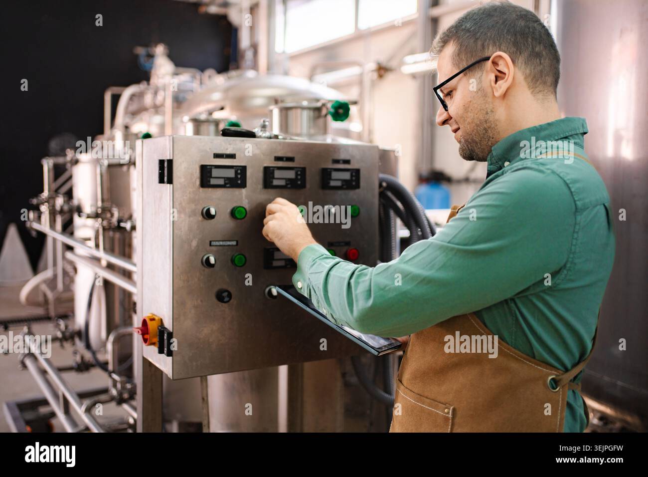 Man working on control panel in modern brewery Stock Photo