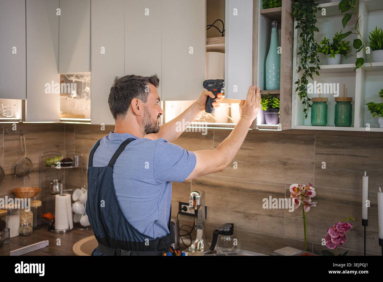 Carpenter working on a new kitchen using a cordless screwdriver Stock Photo