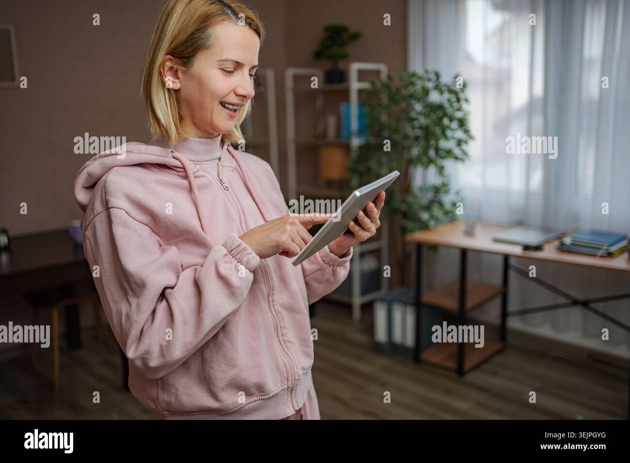 Woman smiling using digital tablet at home Stock Photo