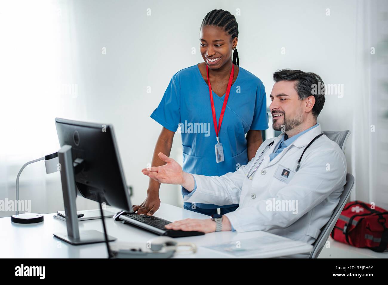Doctors and nurses collaborating in medical office using computer Stock Photo