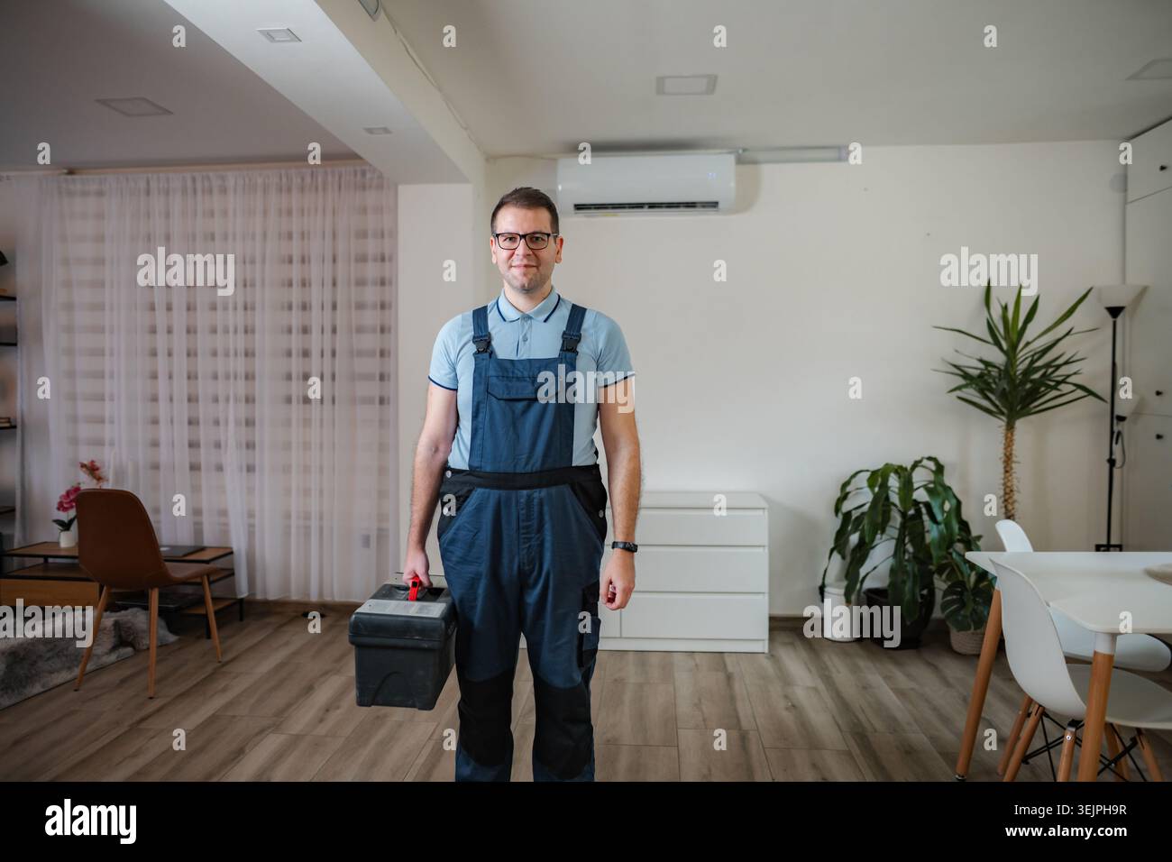 Technician holding toolbox standing in living room Stock Photo