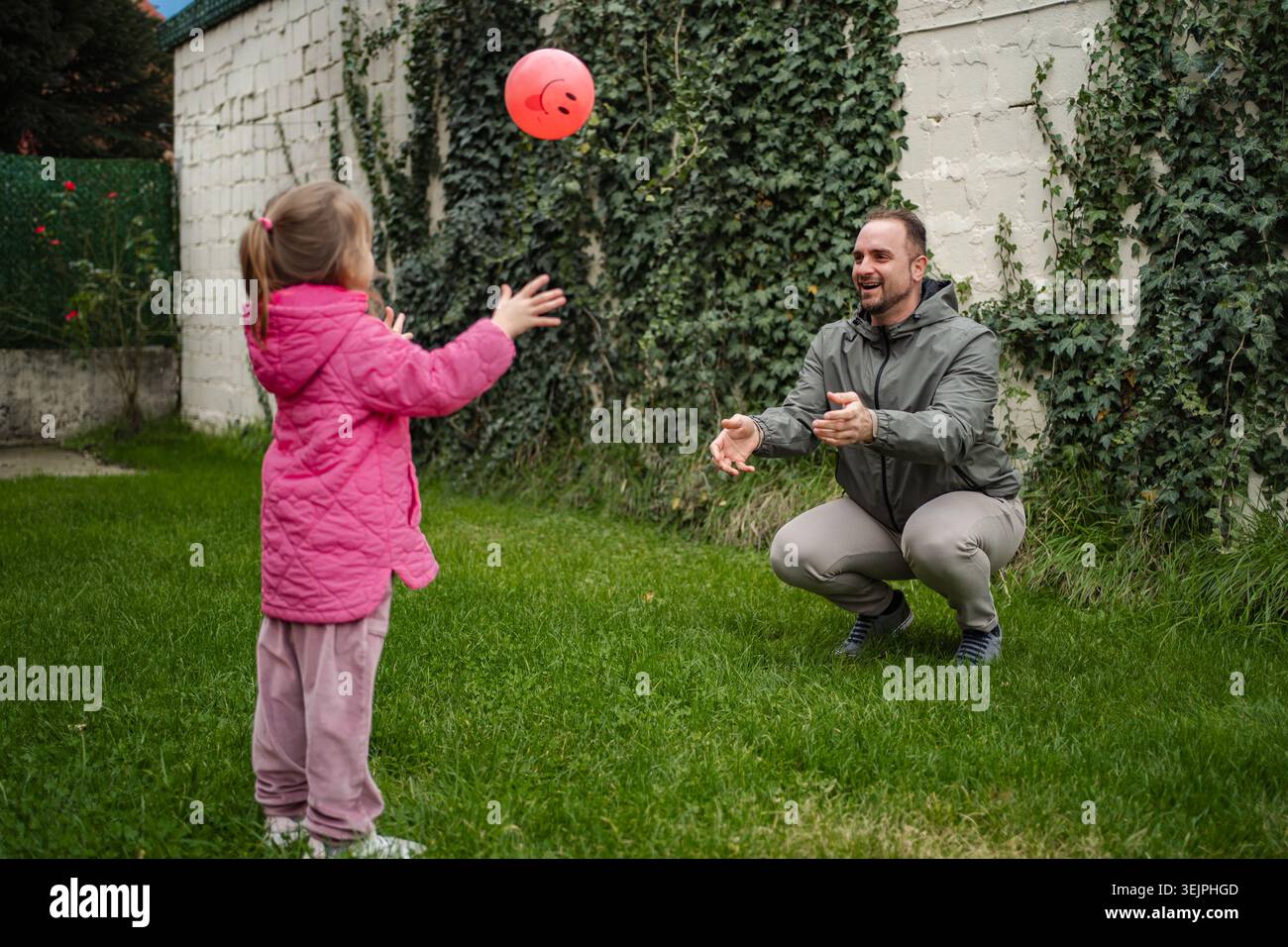 Father daughter playing catch with ball in backyard Stock Photo