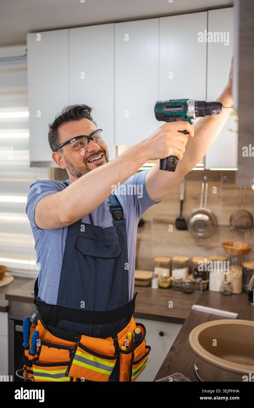 Handyman Using Cordless Drill Installing Kitchen Cabinets Stock Photo