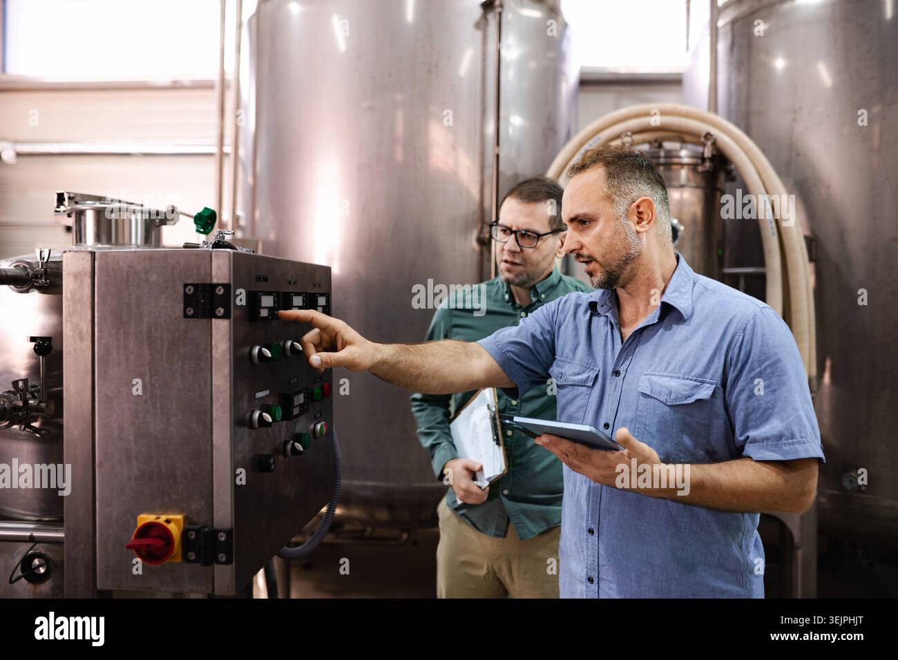 Men operating industrial control panel in brewery factory Stock Photo