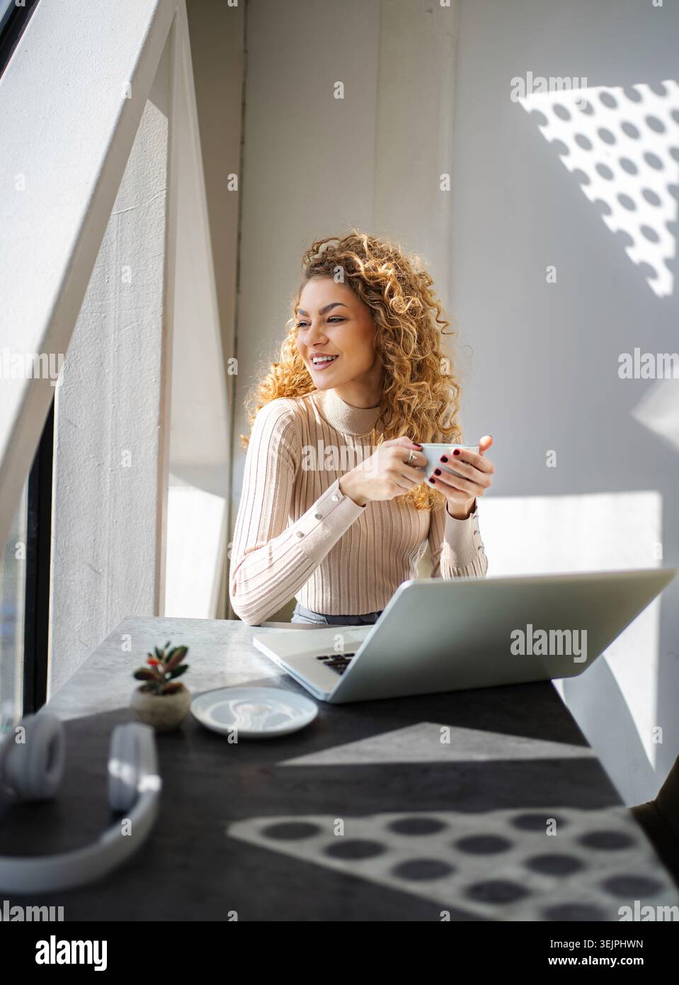 Happy young woman drinking coffee pausing from work Stock Photo