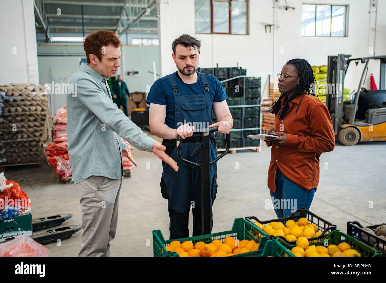 Warehouse workers discussing logistics and fresh fruit inventory Stock Photo