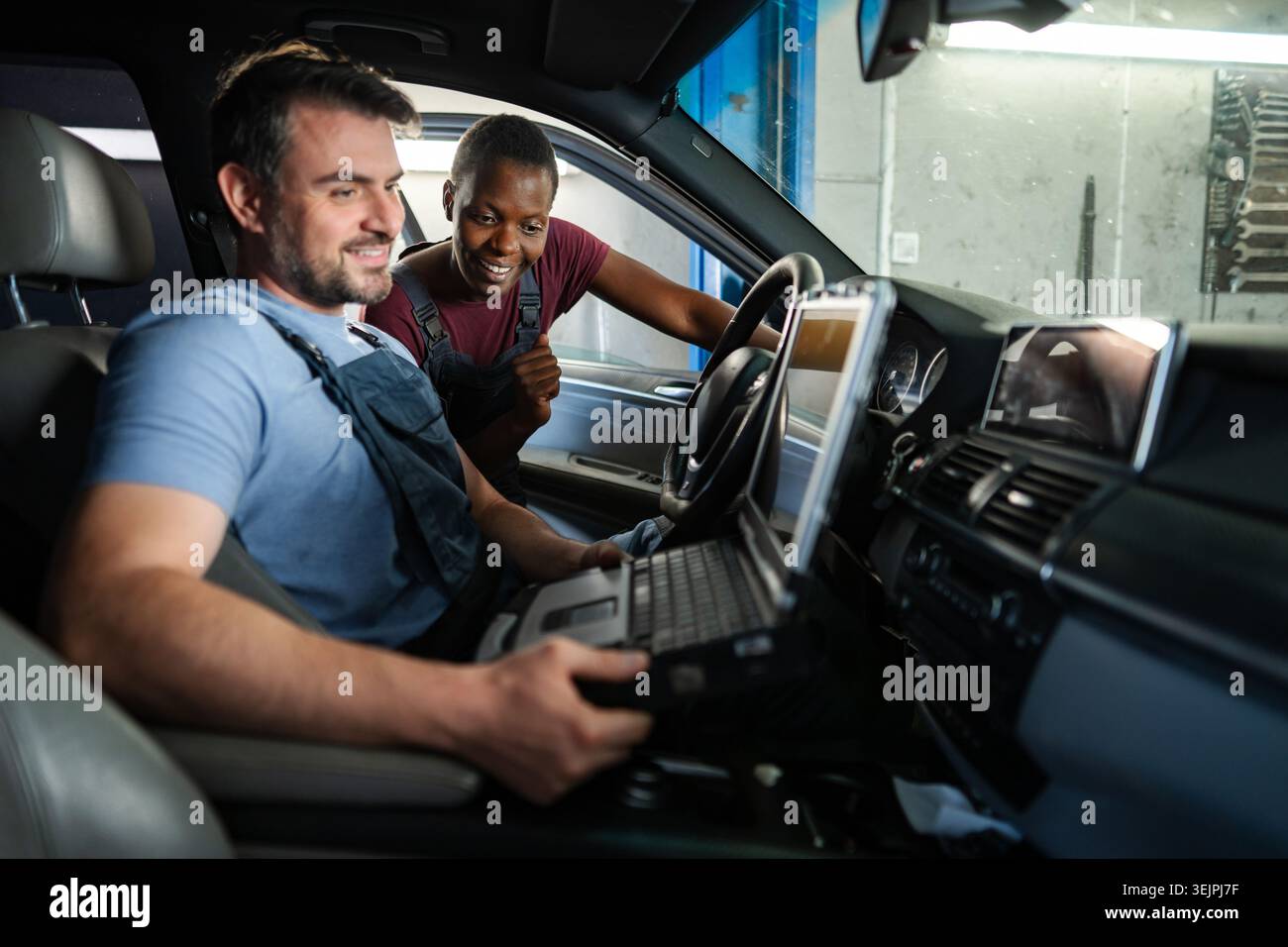 Mechanics performing diagnostics on a car's electronics using a computer Stock Photo
