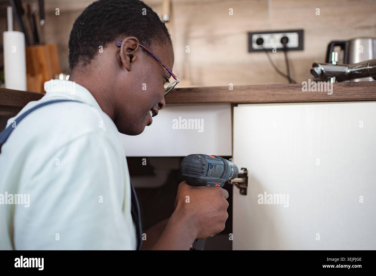 Handyman Installing Kitchen Cabinet Using Cordless Drill Stock Photo
