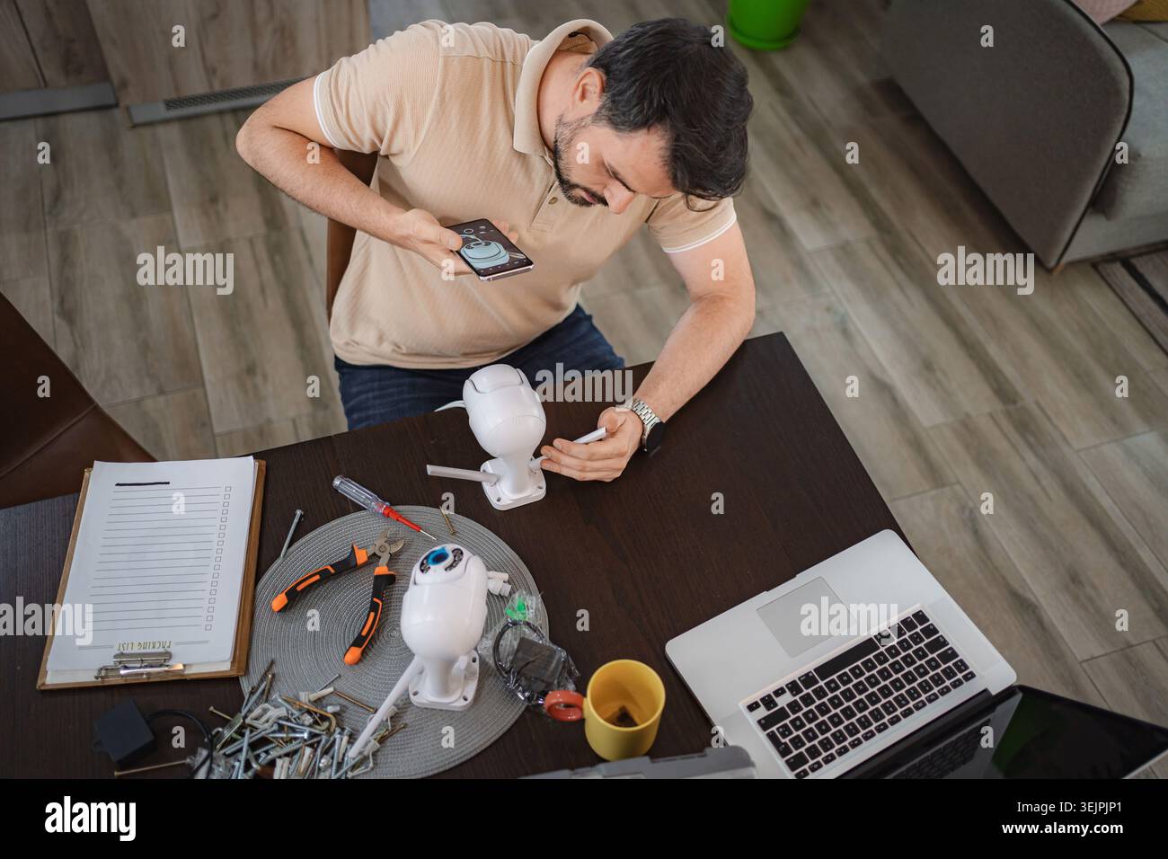 Man installing security camera at home using smartphone app Stock Photo