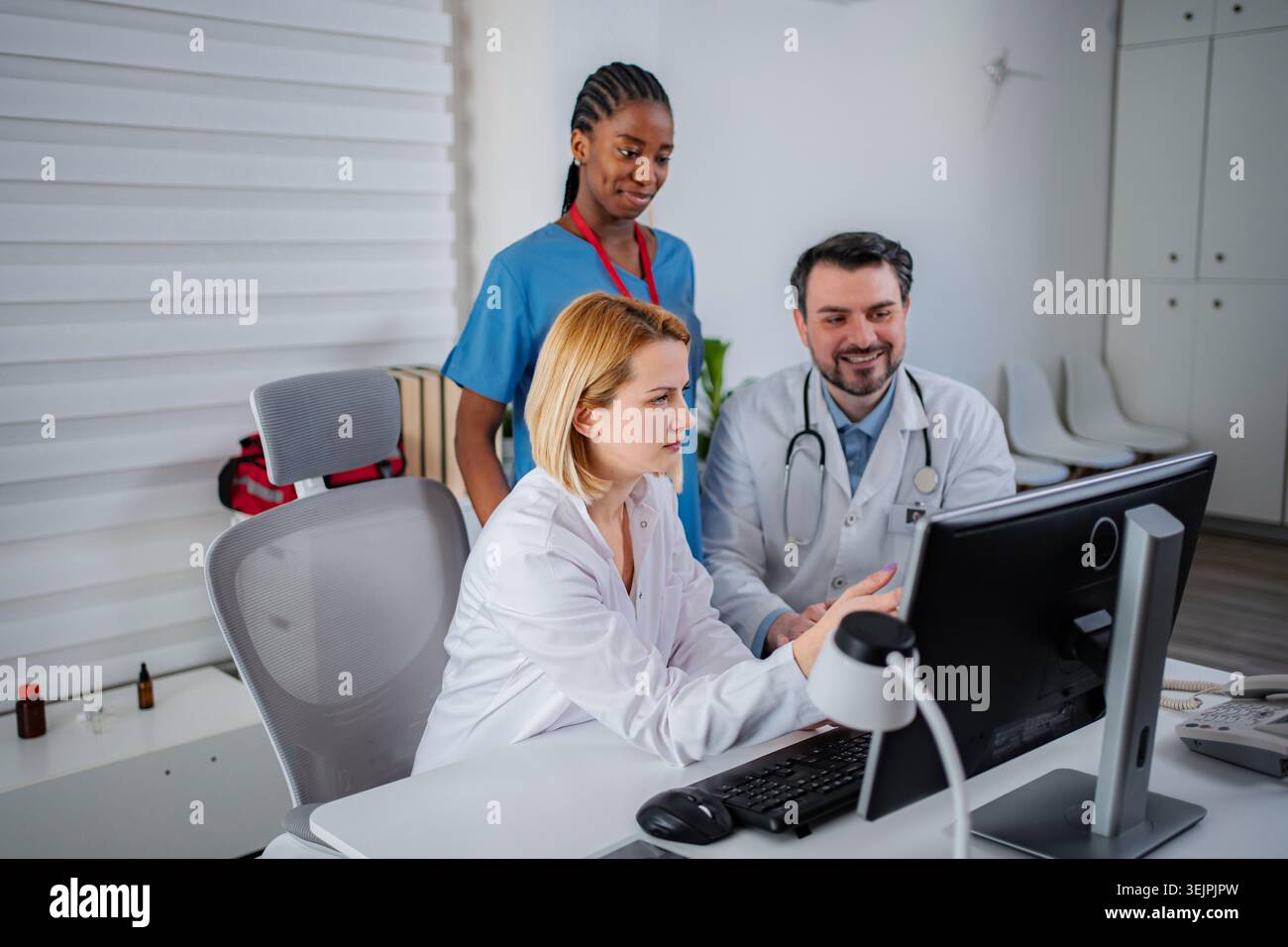 Diverse medical professionals collaborating on patient data using a computer Stock Photo
