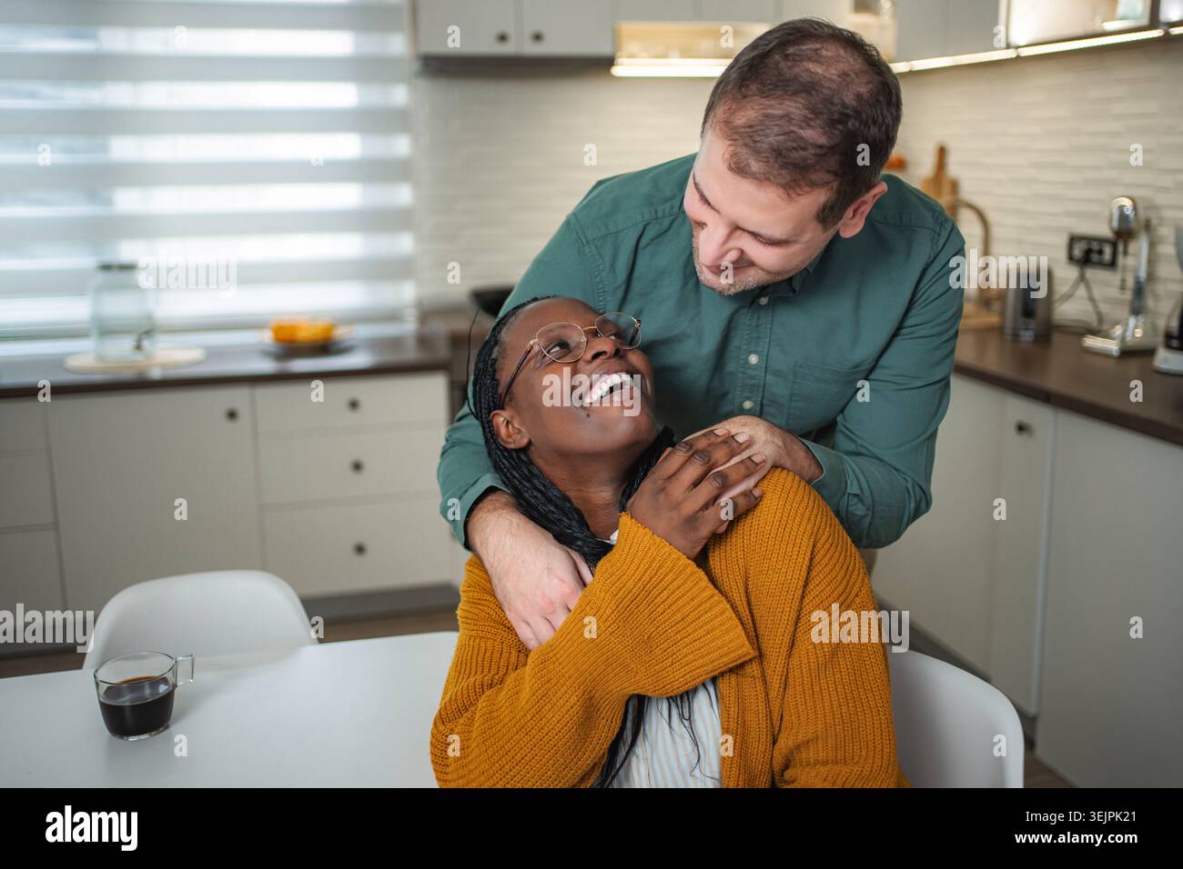 Interracial couple sharing happy morning moment in kitchen Stock Photo
